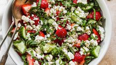 a salad with strawberries, cucumbers and feta cheese in a white bowl