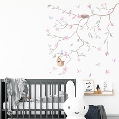 a baby's room with a white crib and pink flowers on the wall