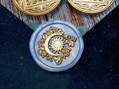 two gold and blue medallions sitting on top of a wooden table next to each other