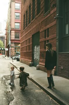 a woman walking down the street with two small children