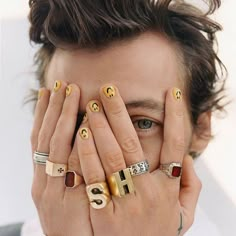 a man holding his hands to his face with different rings on it's fingers