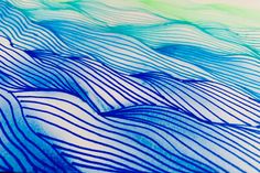 blue and green wavy lines are shown on the surface of a paper sheet that has been drawn