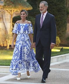 a man and woman in formal wear walking down the street with one holding his hand