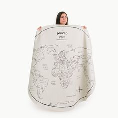 a woman is holding up a world map blanket