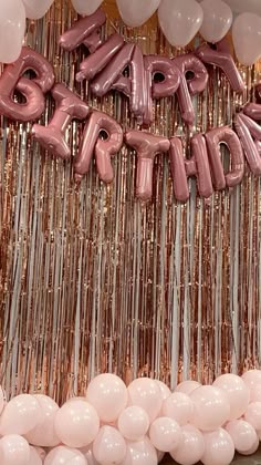 balloons and streamers are arranged in front of a happy birthday sign