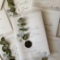 the wedding stationery is laid out on top of each other with eucalyptus leaves and wax stamp