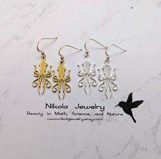 Squid Earrings in Gold or Silver Purchase includes a natural jewelry box and gift packaging. Gift? Add-on a hummingbird card for only $7: https://www.etsy.com/listing/202506976/nikola-jewelry-hummingbird-card Add-on extender: https://www.etsy.com/listing/197483038/add-on-necklace-extender-chain-with Necklace longer than 20 inches: https://www.etsy.com/listing/196689227/extend-my-necklace-up-to-30-inches Turn pendant into a keychain or ornament: https://www.etsy.com/listing/1003597263/turn-any-pe Themed Gold Earrings For Gifts, White Themed Jewelry Gift, Themed White Jewelry For Gifts, Squid Earrings, Hummingbird Card, Biology Jewelry, Earring Inspo, Octopus Pendant, Geek Jewelry