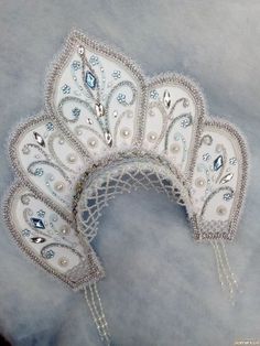 a close up of a white mask with beads on it's sides and an intricate design