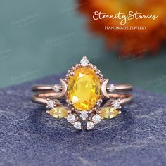 an oval yellow sapphire and diamond ring on top of a blue stone surface with flowers in the background