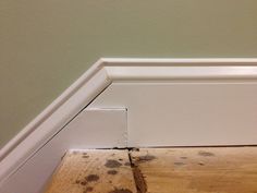 the corner of a room with wood flooring and moldy paint on the walls