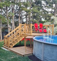 an above ground swimming pool with steps leading up to the deck and red chairs around it