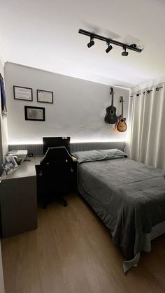 a bed room with a neatly made bed and guitar hanging on the wall