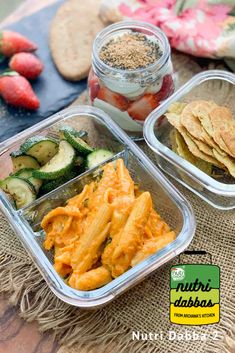 three plastic containers filled with food sitting on top of a wooden table next to strawberries