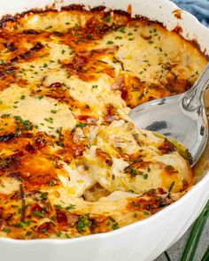 a close up of a casserole in a white dish with a serving spoon