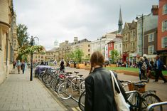 there are many bikes parked on the side of the street and people walking down the sidewalk