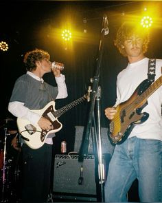 two young men playing guitars and singing into microphones