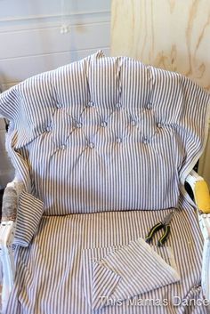 a striped chair is being worked on with scissors and fabric in the process of reupholing it