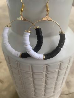 two black and white hoop earrings with gold accents on top of a glass vase filled with water