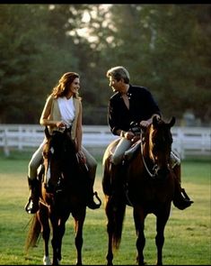 two people riding on the backs of brown horses