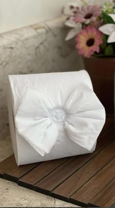 a white box with a bow on it sitting on a table next to some flowers