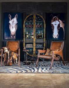 two chairs and a table with pictures on the wall behind them in front of a zebra print rug