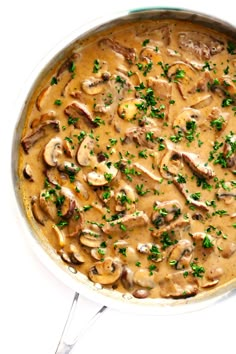 a pan filled with mushrooms and gravy on top of a white countertop