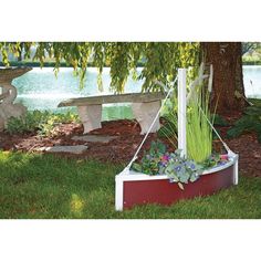 a planter with flowers in it sitting under a tree next to a park bench