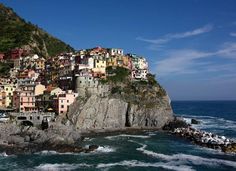 the colorful houses are perched on top of the cliff by the water's edge