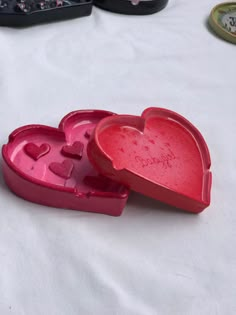 two heart shaped boxes sitting on top of a white tablecloth covered table with other items