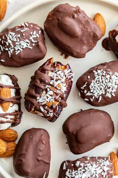 chocolate covered desserts are arranged on a plate with nuts and almonds around them