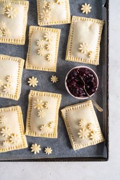 homemade pastries on a baking sheet with blueberry sauce