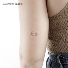 a woman's arm with a small crab tattoo on the left side of her arm