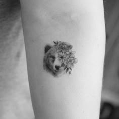 a black and white photo of a bear with flowers on it's back arm