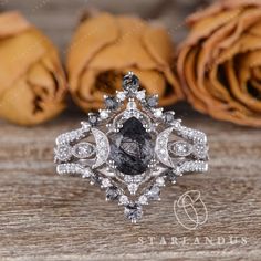 a black and white diamond ring sitting on top of a wooden table next to roses