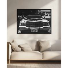 a living room with a white couch and a black and white photo on the wall