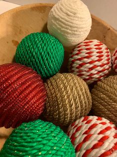 several balls of yarn are in a bowl on the table, one is red and green