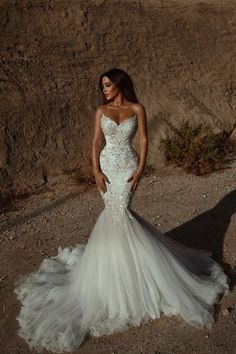 a woman in a wedding dress standing next to a cliff