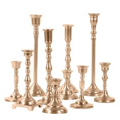 a group of gold colored candlesticks sitting next to each other on a white background