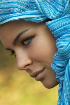 a woman wearing a blue turban with her hair pulled back and eyes closed