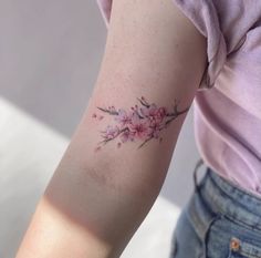 a woman's arm with pink flowers and leaves on the left side of her arm