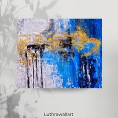 an abstract painting with blue, yellow and white colors is displayed on a gray wall