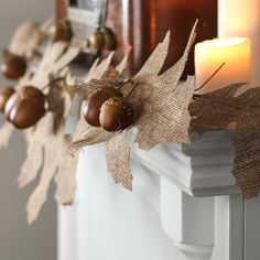 a candle is lit on a mantle with burlap leaves and acorns