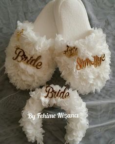 two white slippers with bride and groom written on them are laying on a bed