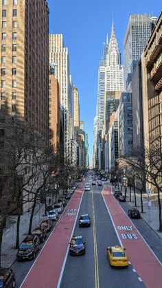 an empty city street with cars parked on both sides and tall buildings in the background