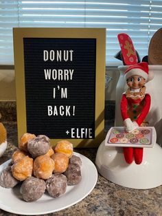 an elf with donuts and doughnut holes next to a sign that says donut worry i'm back