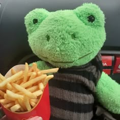 a green frog stuffed animal sitting next to a pile of fries