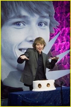 a man standing in front of a cake on top of a table