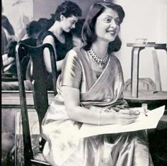 an old black and white photo of two women sitting at a table with papers in front of them