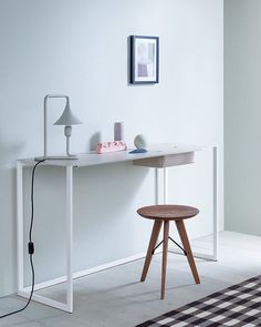 a white desk with a lamp on it and a checkered rug in front of it