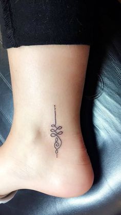 a woman's foot with a small tattoo on the side of her leg and an arrow in the middle